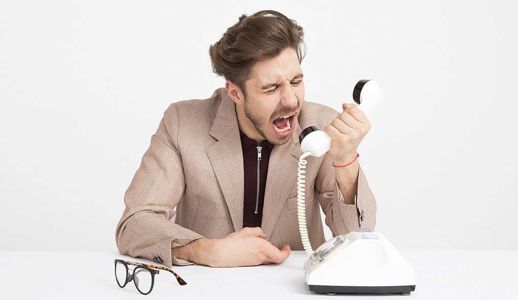 man screams in white telephone angrily with his eye glasses sitting on the table