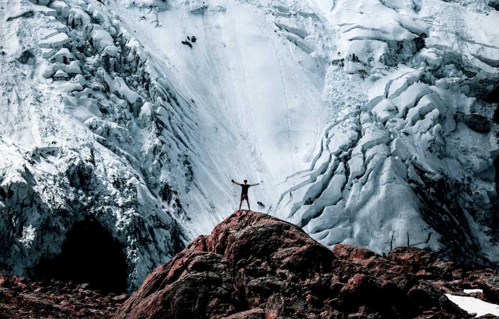 Man stands celebrating in front of a massive avalanche